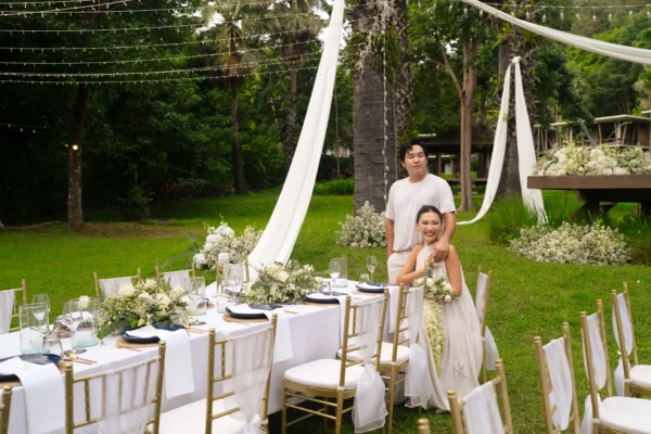 Bride and groom in white wedding attire seated at an outdoor banquet table for a Western Wedding Package at Veranda High Resort Chiang Mai.