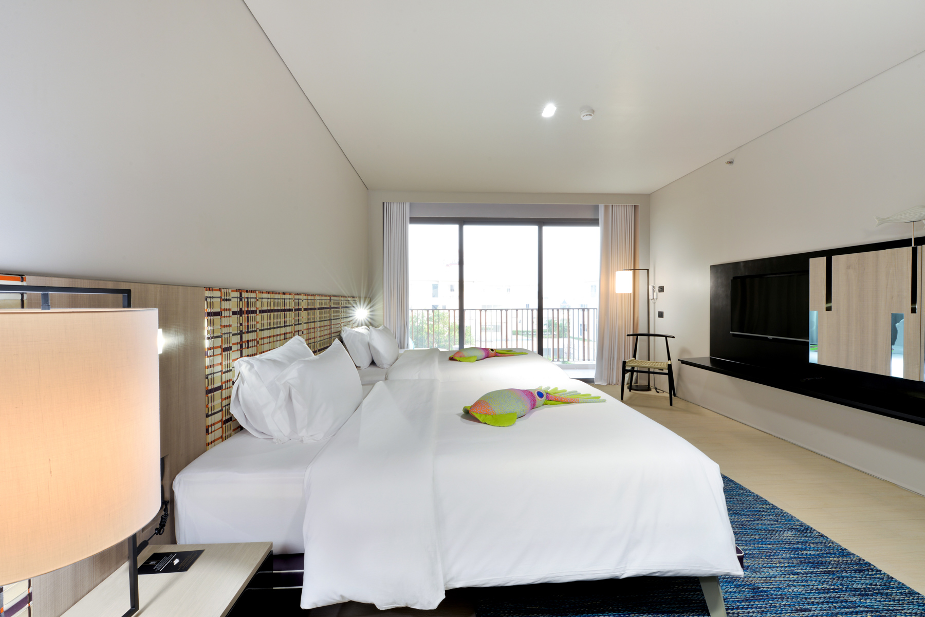 Spacious Seascape Deluxe featuring double queen beds, warm lighting, and soft neutral tones for a serene beachfront retreat in Na Jomtien.