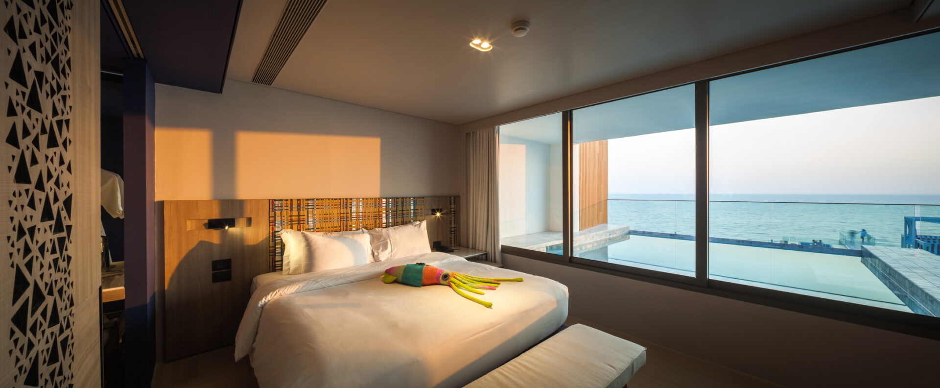 Stylish master bedroom in the Sky Pool Villa featuring ocean-facing windows and luxury furnishings.